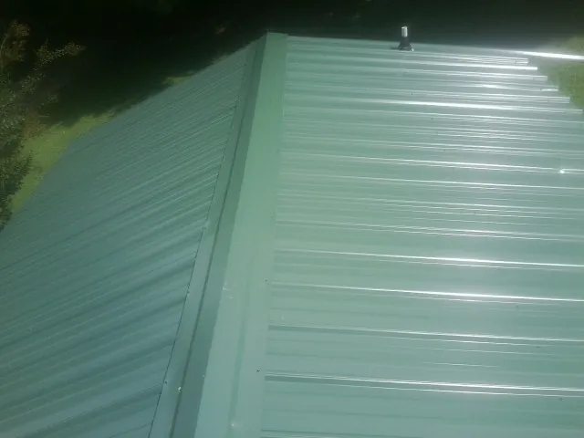 New green metal panels meeting at the ridge of a roof — Flat Roof Repair work by our crew in Callahan