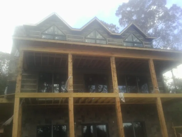 Dormers and porch framing on a large log home under construction — Roof Coating work by our crew in Callahan