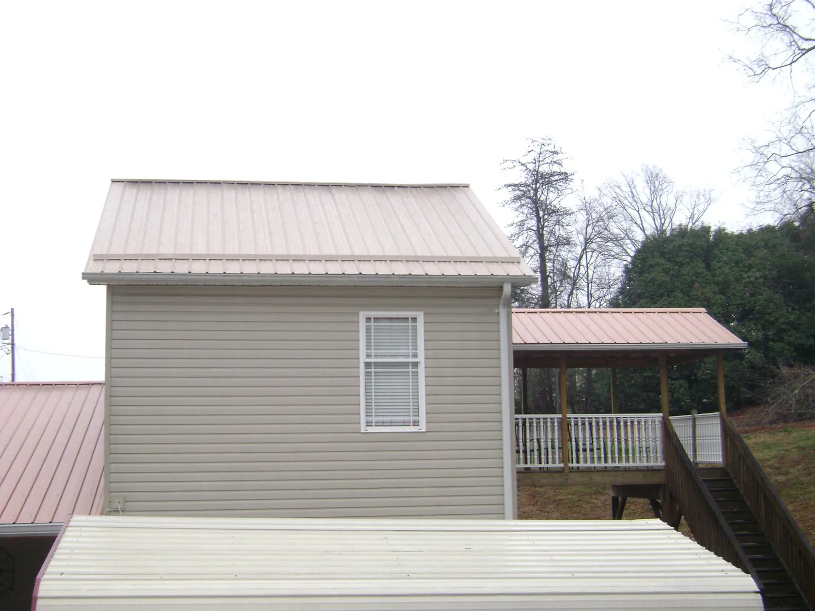 Tan metal roofs on a two story addition and attached porch, from a Roof Replacement job in Callahan